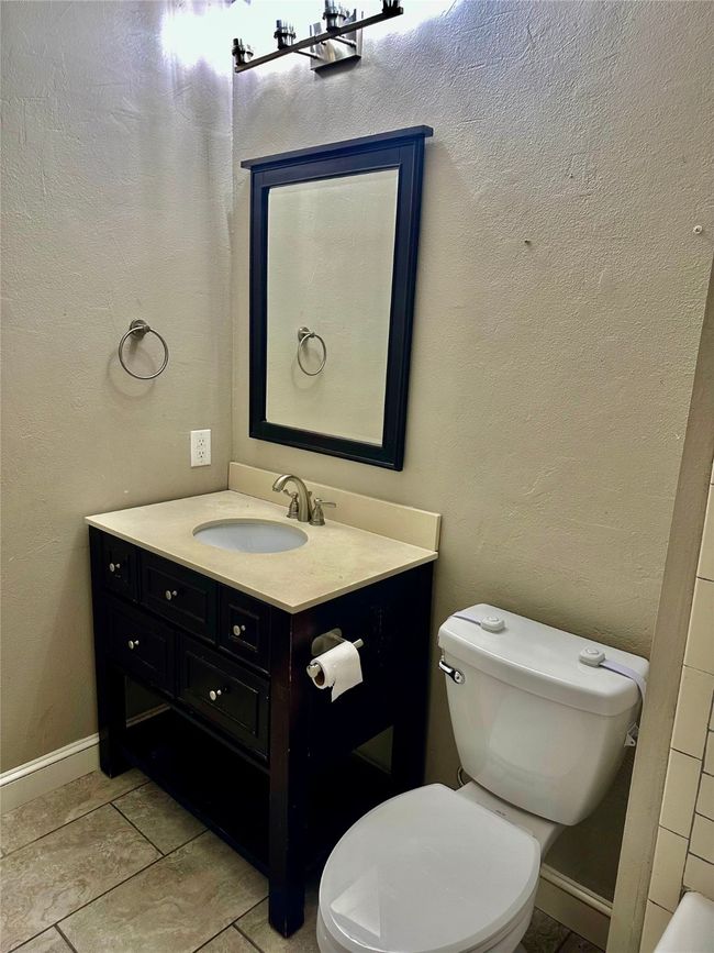 Bathroom with a textured wall, vanity, and tile patterned flooring | Image 21