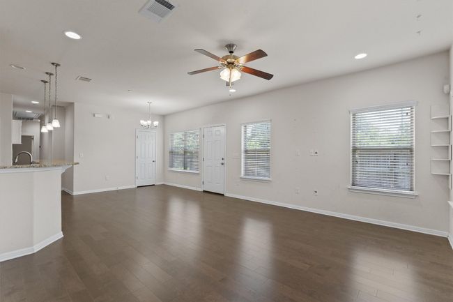 Unfurnished living room featuring a ceiling fan, a chandelier, baseboards, recessed lighting, and dark wood-style floors | Image 6