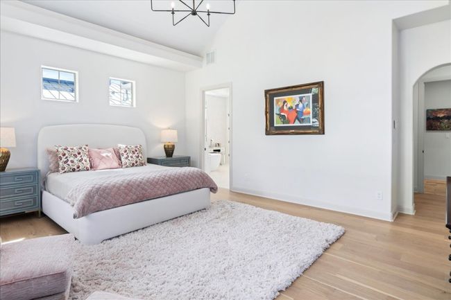 Bedroom featuring a chandelier, arched walkways, light wood finished floors, and high vaulted ceiling | Image 16
