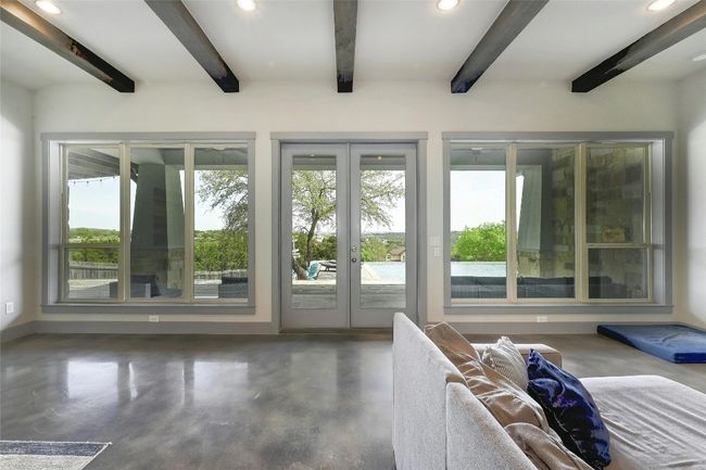 A wall of windows and doors frames in the outdoor living, pool, and skyline. | Image 9
