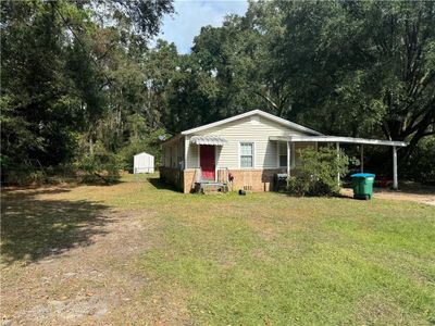 View of front facade featuring a storage shed, a carport, and a front lawn | Image 1