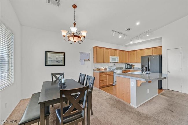 Kitchen featuring white appliances, light colored carpet, a chandelier, and plenty of natural light | Image 8