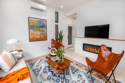 The living area exudes brightness and warmth with its wide plank white oak floors, and a cozy fireplace. | Image 2