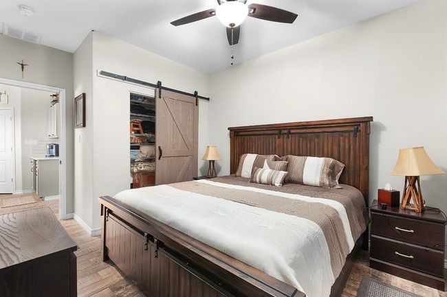 Bedroom featuring a ceiling fan, visible vents, baseboards, light wood-style flooring, and a barn door | Image 17