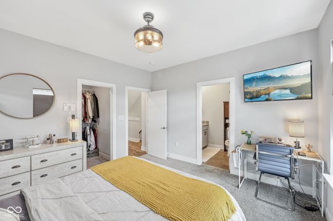 bedroom with a closet, light carpet, a walk in closet, ensuite bathroom, and baseboards | Image 13