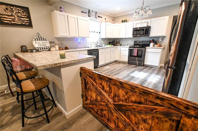 Kitchen with appliances with stainless steel finishes, a peninsula, a sink, wood finished floors, and a chandelier | Image 16