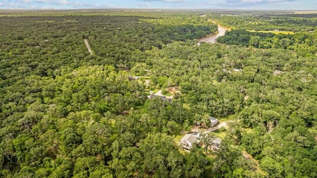 High-elevation view looking across the property, illustrating dense canopy coverage, the curving drive and nearby Brazos River corridor. | Image 41