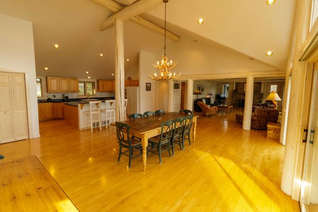 Dining room with a notable chandelier, a brick fireplace, high vaulted ceiling, and light wood-type flooring | Image 34