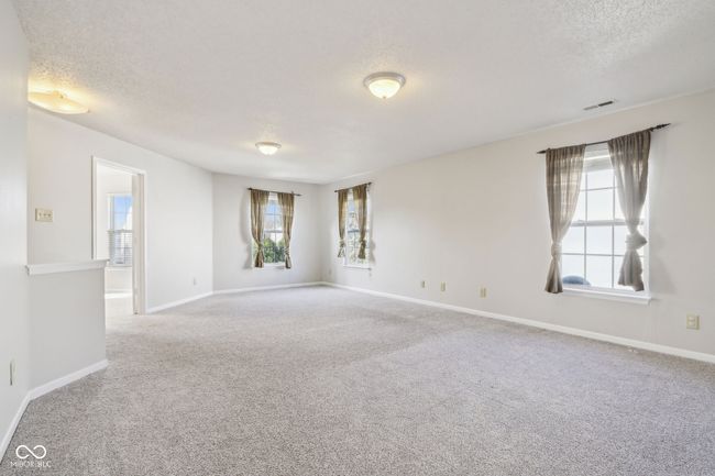 carpeted empty room with healthy amount of natural light, a textured ceiling, and baseboards | Image 53