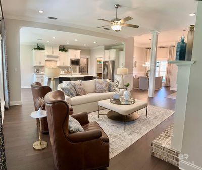 Living room with sink, crown molding, decorative columns, dark wood-type flooring, and ceiling fan | Image 2