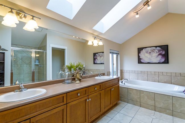 Bathroom with a sink, lofted ceiling with skylight, tile patterned floors, and a stall shower | Image 19