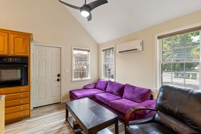 Living room featuring wood finished floors, a healthy amount of sunlight, an AC wall unit, and vaulted ceiling | Image 5