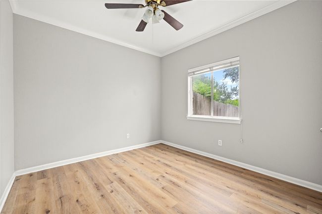 crown molding, light wood-type flooring, a ceiling fan, and baseboards | Image 17