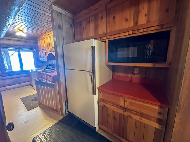 Kitchen with white fridge, wooden ceiling, and rustic walls | Image 21