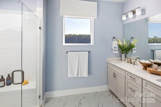 *This image is not of the actual home, but a photo of our model home, shown for representative purposes.* Luxurious primary bathroom featuring a spacious walk-in shower, dual sinks, a private water closet, and a generous walk-in closet. | Image 9