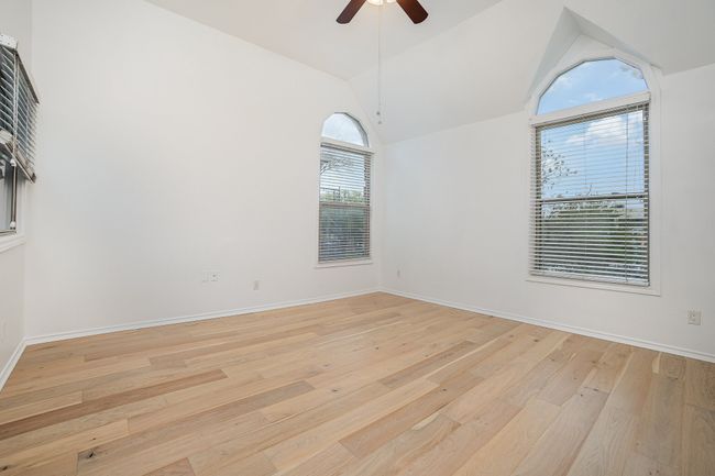 Empty room featuring baseboards, vaulted ceiling, light wood-type flooring, and a ceiling fan | Image 11