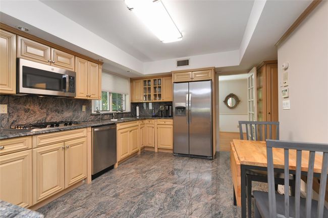 Kitchen with glass insert cabinets, visible vents, a sink, backsplash, and appliances with stainless steel finishes | Image 7