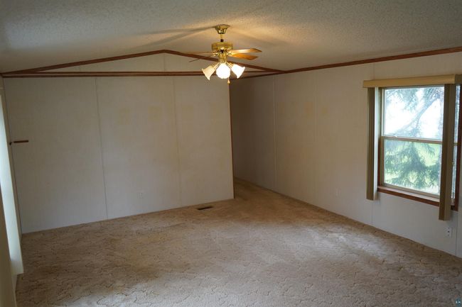 Carpeted spare room with ceiling fan, vaulted ceiling, and a textured ceiling | Image 13