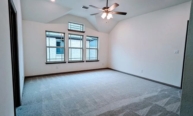 Carpeted empty room featuring baseboards, a ceiling fan, vaulted ceiling, and visible vents | Image 14