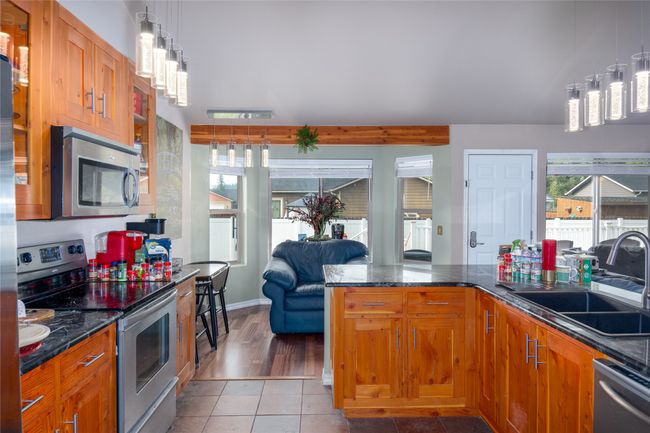 Kitchen with decorative light fixtures, a sink, brown cabinetry, stainless steel appliances, and tile patterned floors | Image 42