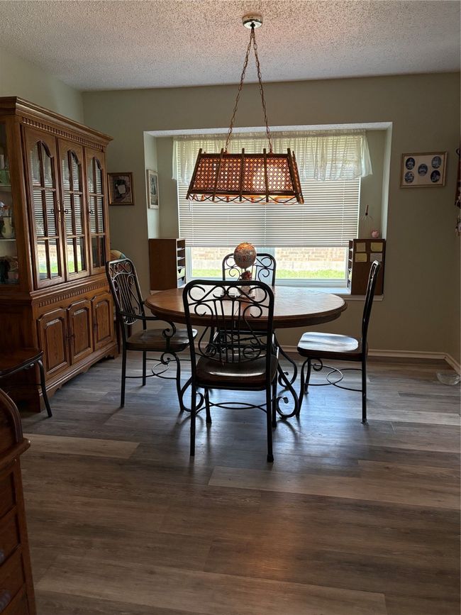 Dining area with a textured ceiling and dark wood-style flooring | Image 5