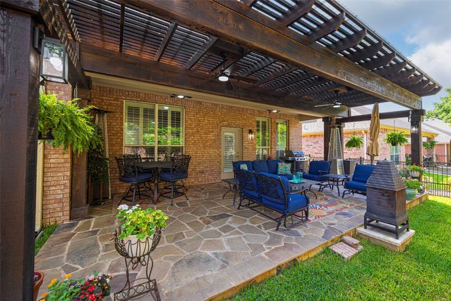 Fenced backyard featuring a pergola, an outdoor hangout area, ceiling fan, perfect for relaxing and entertaining. | Image 25