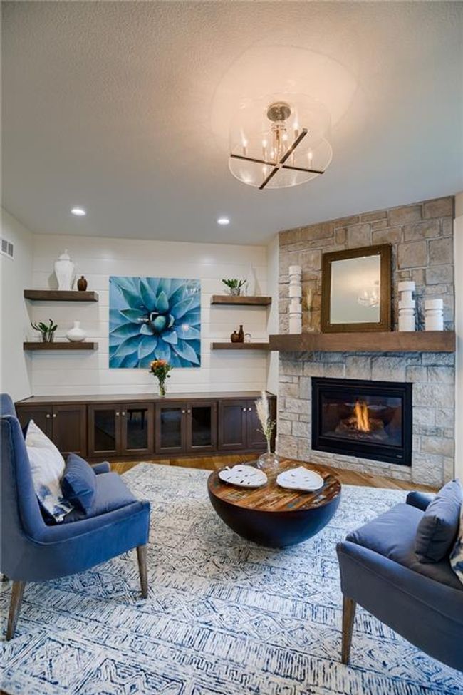 Living room featuring a chandelier, a textured ceiling, and a fireplace | Image 12