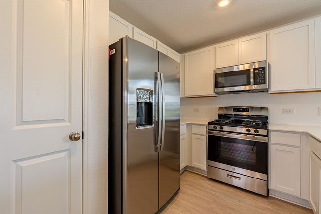 Kitchen with stainless steel appliances, light countertops, and white cabinetry | Image 7