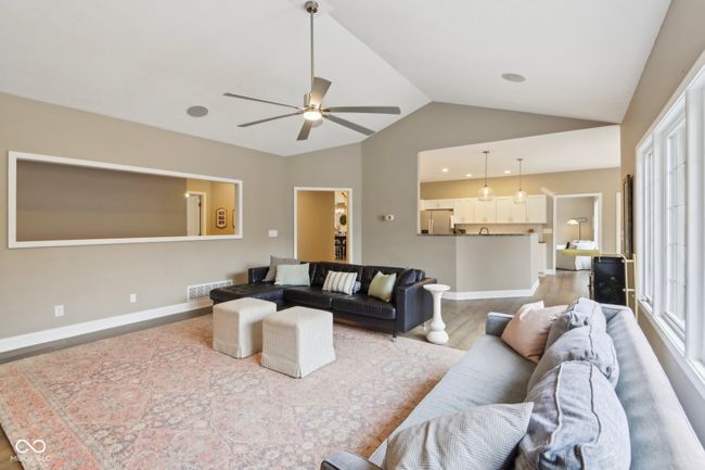 living area featuring vaulted ceiling, baseboards, visible vents, a ceiling fan, and wood finished floors | Image 23