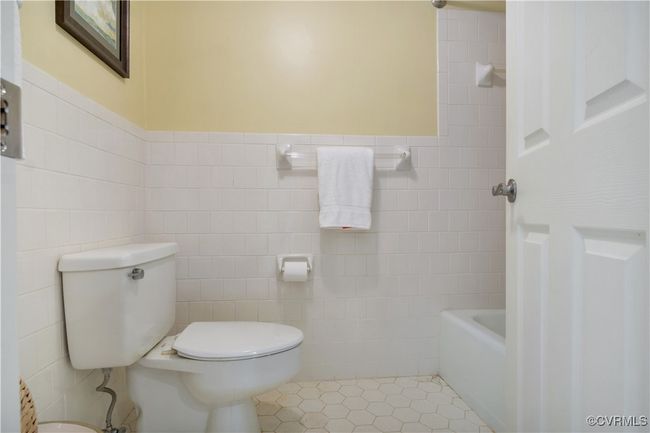 Bathroom with toilet, tile patterned floors, tile walls, and a bathtub | Image 26