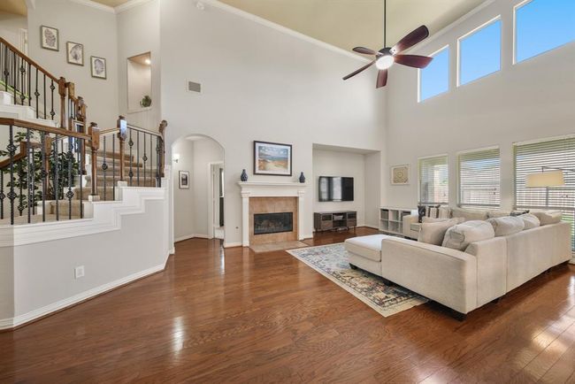 Perfect for an entertainment center is a recessed wall sitting just next to the tile surrounded gas log fireplace with mantel & tiled hearth. The arched opening in the background offers access to a vestibule illuminated by wall sconce lighting leading the way to the owner's suite. | Image 11