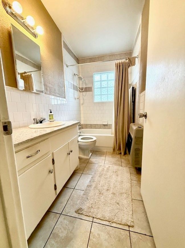 Bathroom with vanity, shower / tub combo with curtain, toilet, backsplash, and tile patterned floors | Image 16
