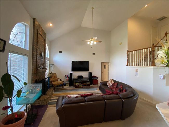 Living room with a fireplace, carpet, high vaulted ceiling, and ceiling fan | Image 12