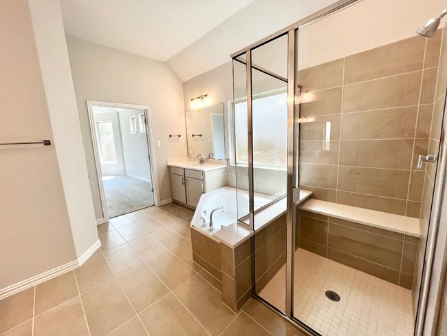 Full bath featuring vanity, a shower stall, a garden tub, light tile patterned flooring, and vaulted ceiling | Image 15