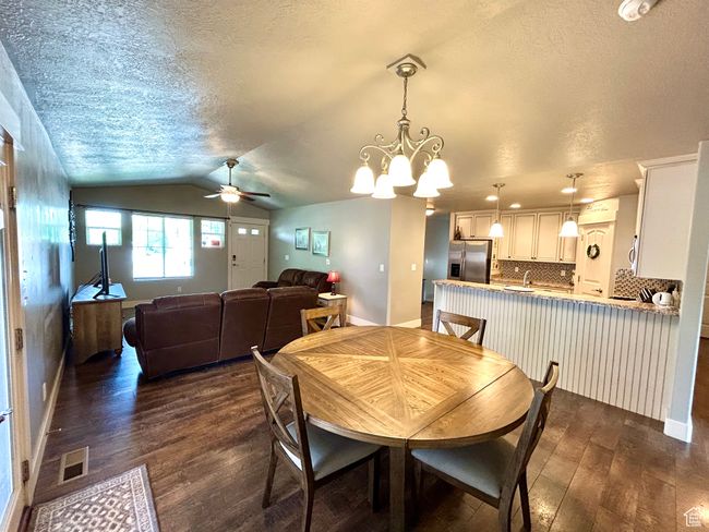 Dining room featuring dark wood-style flooring, ceiling fan, a textured ceiling, baseboards, and lofted ceiling | Image 9