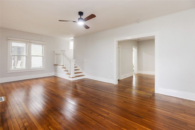 Front room featuring ceiling fan, stairway, hardwood / wood-style floors, baseboards, and crown molding | Image 4