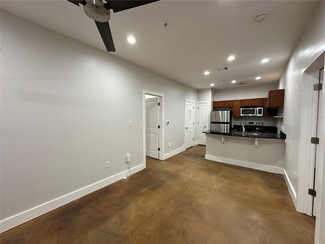 Kitchen featuring dark countertops, ceiling fan, a kitchen bar, finished concrete floors, and recessed lighting | Image 15