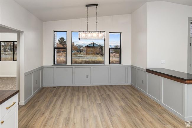 Unfurnished dining area featuring an inviting chandelier, lofted ceiling, and light wood-type flooring | Image 7