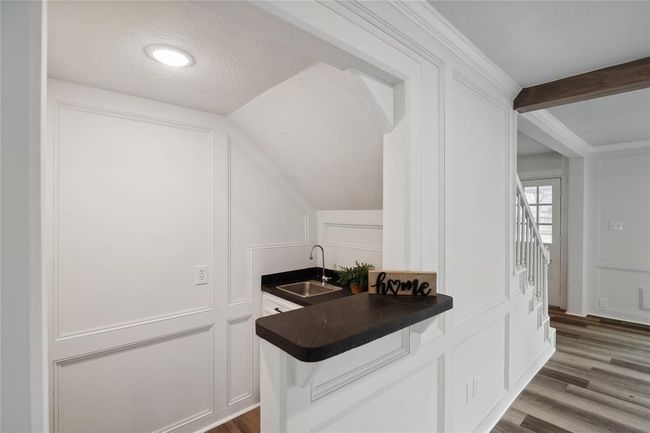 This ideally located wet bar has white paneled walls, a sink and counter space, as well as underneath storage space. | Image 8