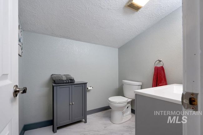 Half bathroom with vanity, a textured ceiling, vaulted ceiling, and a textured wall | Image 25