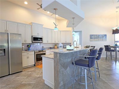 Kitchen featuring light granite counters, appliances with stainless steel finishes, pendant lighting, and white cabinets | Image 3