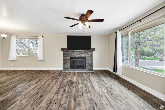 Unfurnished living room with wood finished floors, a ceiling fan, a fireplace, and baseboards | Image 8