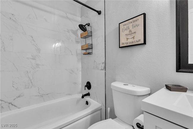 Full bath with shower / tub combination, a textured wall, toilet, and vanity | Image 29
