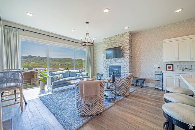 Living area with light wood finished floors, a chandelier, a stone fireplace, and recessed lighting | Image 4
