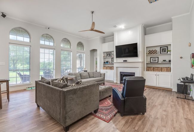 Living area featuring ornamental molding, light wood finished floors, ceiling fan, a tile fireplace, and arched walkways | Image 15