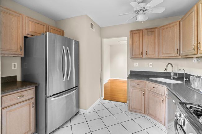 Kitchen featuring stainless steel appliances, a sink, ceiling fan, dark countertops, and light brown cabinets | Image 10