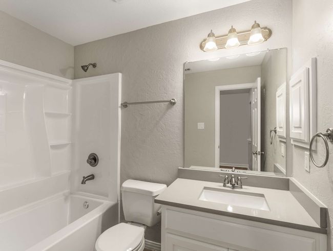 Bathroom featuring shower / bath combination, toilet, vanity, and a textured wall | Image 39