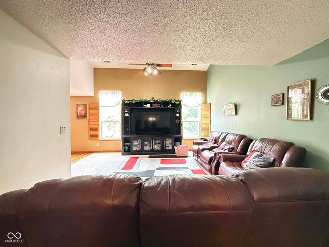 living room featuring a textured ceiling, plenty of natural light, a ceiling fan, and carpet flooring | Image 12