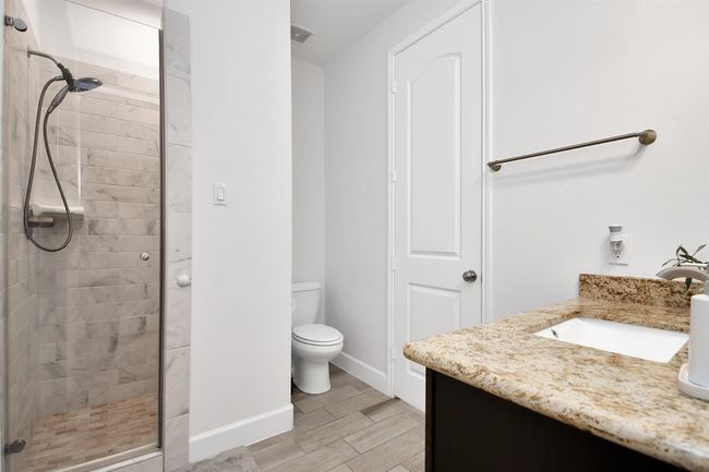 This bathroom features a modern design with a glass-enclosed shower, tiled walls, and a spacious vanity with a granite countertop. The neutral color palette and clean lines create a fresh, inviting atmosphere. | Image 13