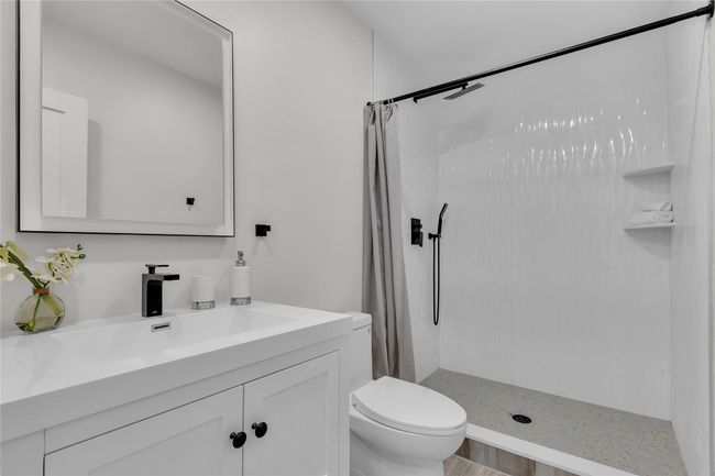 Bathroom with vanity, a shower with shower curtain, and toilet | Image 14